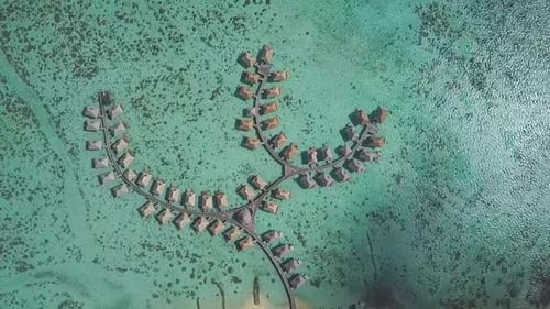 drone flying high over tropical resort overwater bungalows with coral reefs