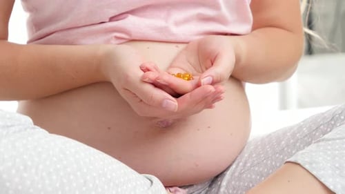 Pregnant Woman Holds Prenatal Vitamin Capsules