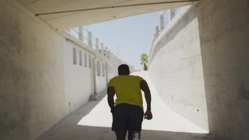 Man Runs Through Urban Concrete Tunnel During Daytime