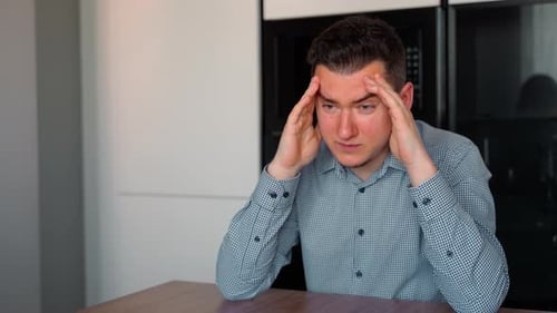 Young Adult Man Massaging Temples Indoors