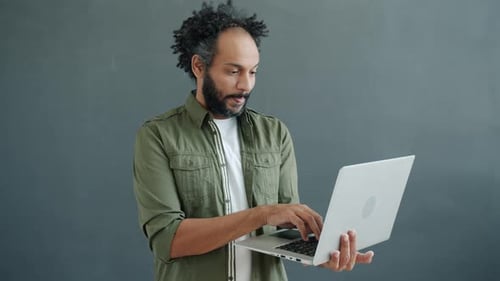Man Holding and Using Silver Laptop Indoors