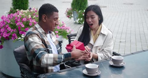 Man gives a gift to his smiling girlfriend