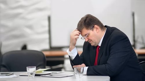 Gestresster Geschäftsmann im Anzug, der im Büro über Finanzprobleme nachdenkt, auf Rot geschossen