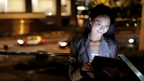 Woman Using Tablet at Night in the City