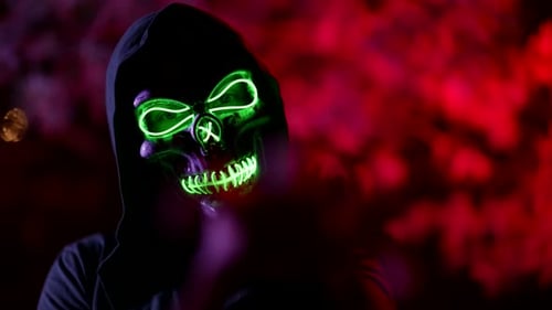 Mysterious Glowing Skull Mask on Face of Enigmatic Man on Street in Night Time