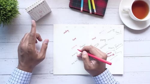 Draufsicht von Man Handschrift auf Wochenplaner auf dem Tisch