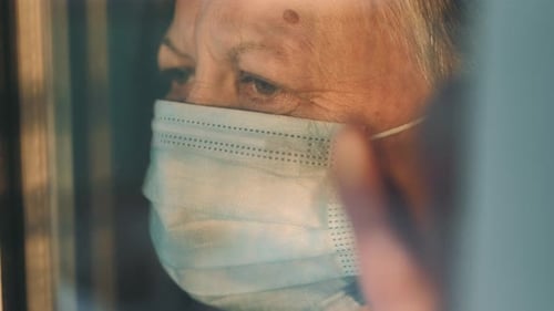 Senior Adult in Surgical Mask Behind Window