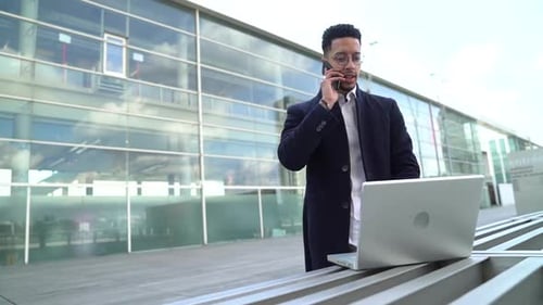 Man Working on Laptop in Front of Building