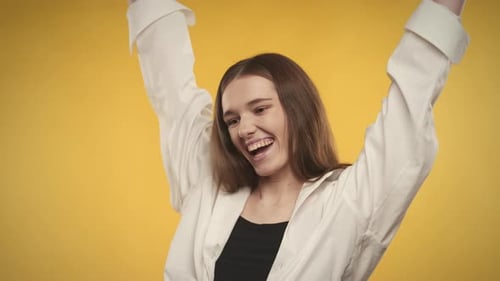 Excited Young Woman Celebrating Against Yellow Background