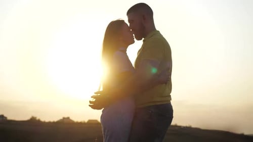 Close View of a Married Young Couple Hugging and Kissing in Nature Against the Horizon of the Sky