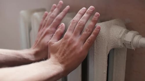 Man Checks the Temperature of the Old Heating Radiator Close Up