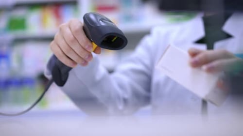 Nicht wiederzuerkennender Apotheker Kassierer Scanning Pillenbox mit Gerät Stretching Medikamente langsam