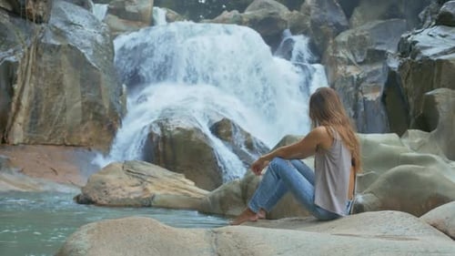 Woman Relaxing by a Waterfall in Nature