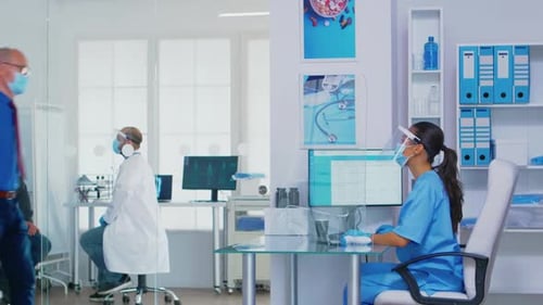 Pushing Disabled Senior Woman in Wheelchair Through Waiting Area