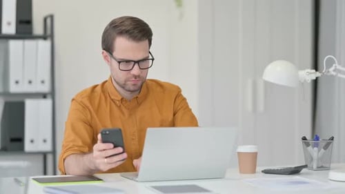 Young Man Using Smartphone in Office