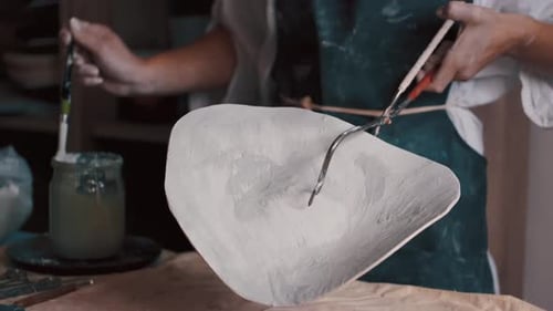 Potter Applying Coating to Ceramic Bowl