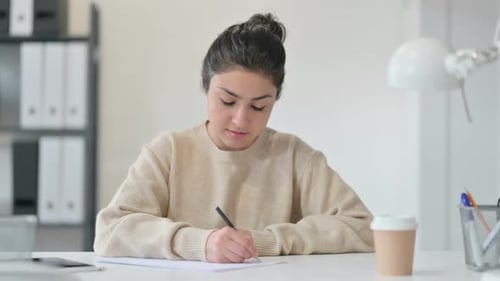 Woman Writing at Desk in Office