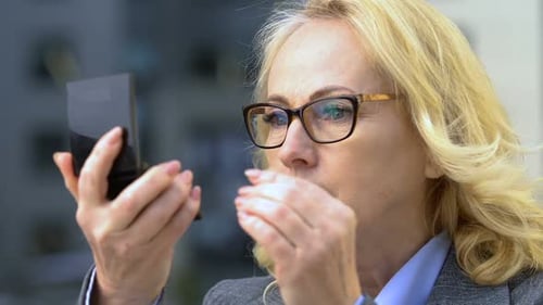 Mature Woman Examining Face in Compact Mirror