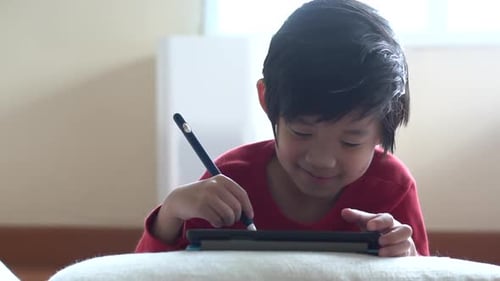 Child Using Stylus Pen on Tablet Device Indoors