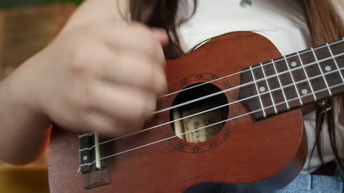 Closeup of Womans Hand Strumming on Ukulele Strings Front View