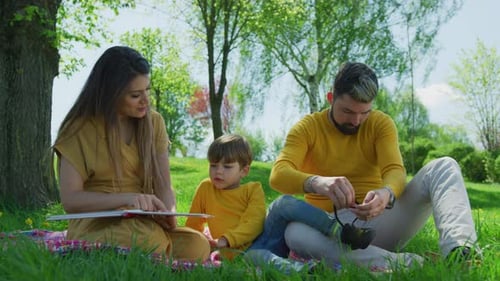 Happy Family Reading and Relaxing in a Park