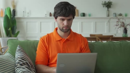 Man Using Laptop Computer While Sitting on Sofa