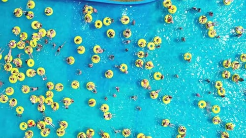 Top View of People Relaxing in the Pool on Yellow Inflatable Circles