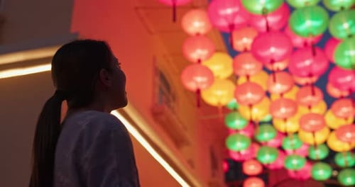 Woman Looks at Lanterns in City at Night