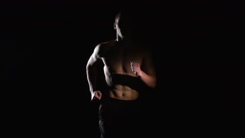 Shirtless Man Running in Place in Dark Room