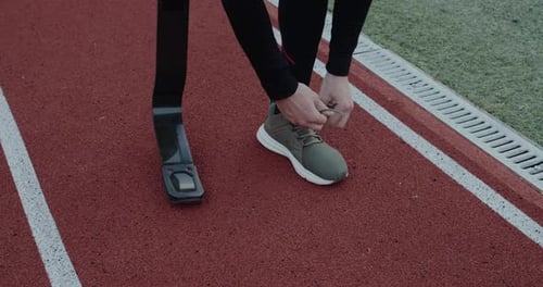 Crop View of Disabled Unknown Male Person with Prosthetic Running Blades Tying Shoelaces and