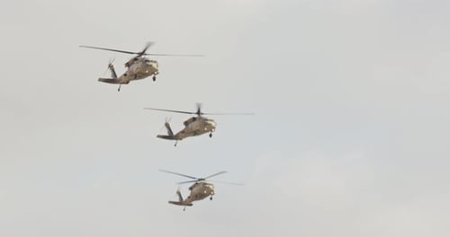 Three Camouflaged Military Helicopters Fly in Formation