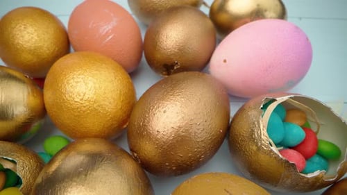 Goldfarben bemalte Ostereier auf blauem Holztisch, Nahaufnahme