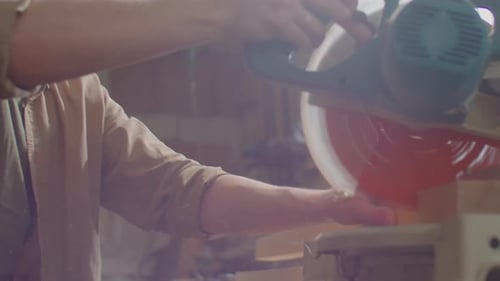 Man Cutting Wood with Saw in Workshop