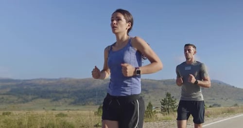 Tracking Slow Motion Shot of Sportive Couple Jogging Outdoors in the Morning Trail Running