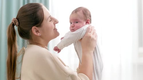 Woman Smiling Holding Cute Baby in Sunny Home