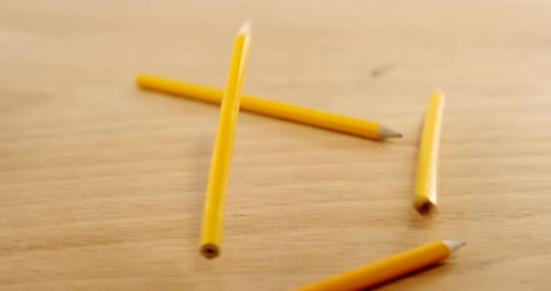 Pencils Falling onto Wooden Table Surface