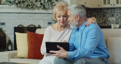 Senior Couple Looking at Tablet Together on Sofa