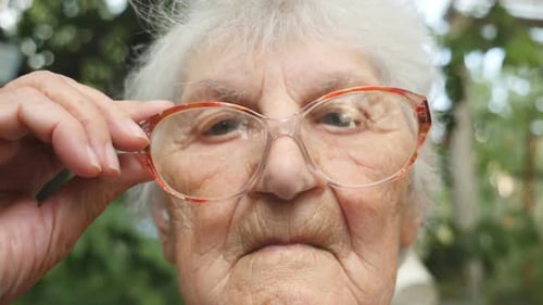 Elderly Woman Adjusts Glasses in Close Up Portrait