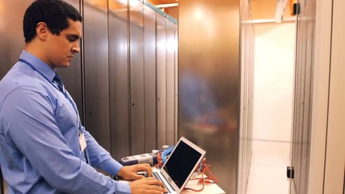 Man Working on Laptop in Server Room