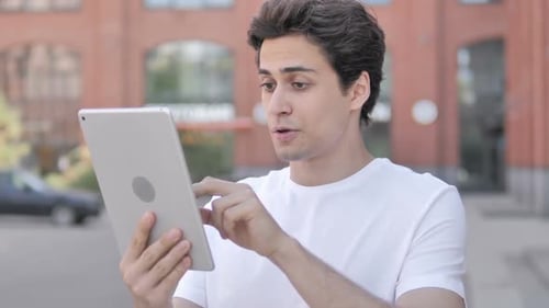Man Celebrating Good News on Tablet Outside