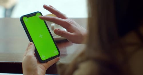 Businesswoman Using Mobile Cell Phone with Green Touch Screen in Cafe. GREEN SCREEN. Sharing