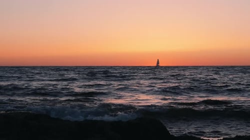 Sailboat is floating in sea at sunset