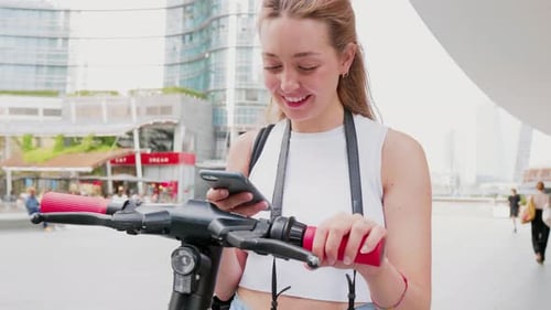 Woman Using Phone with Electric Scooter in City