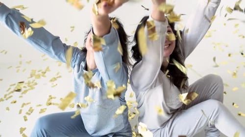 Smiling Women in Pajamas Celebrate with Confetti