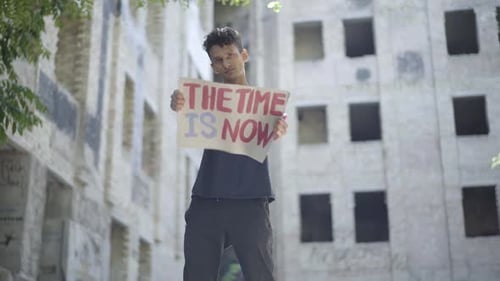 Teen Holds 'The Time is Now' Sign in City