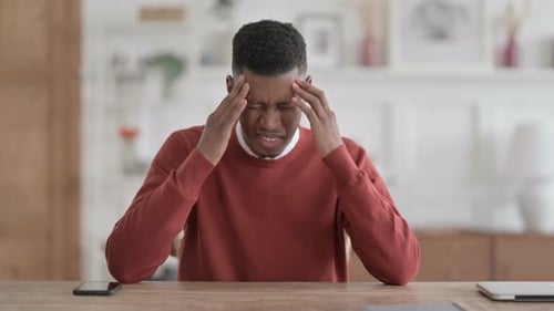 African Man having Headache while Thinking in Office