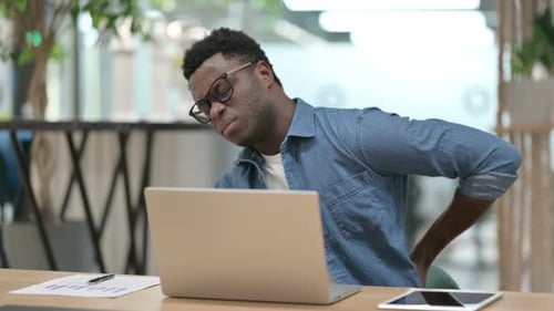 Young Adult Massages Back at Desk in Office
