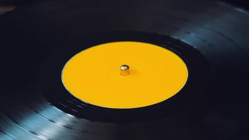 Black Vinyl Retro Record Rotating Plate with Yellow Label on Old DJ Turntable Playe