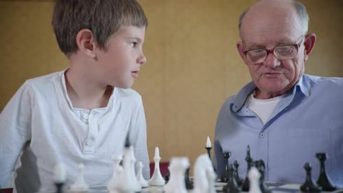 Grandfather and Grandson Play Chess Game Together