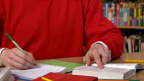 Student Researching with a Book in a Library. Close Up